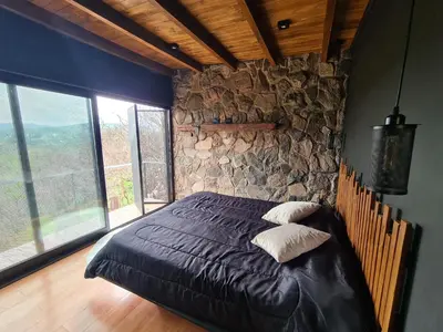 a bedroom with a bed with a stone wall at Chalet - Stone Cabin in Villa Icho Cruz