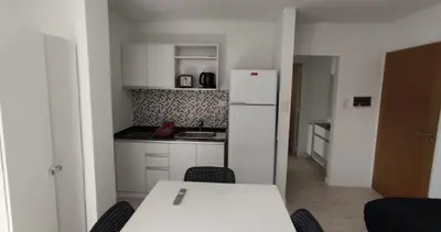 a kitchen with a table and a white refrigerator at Accarezza in Villa Carlos Paz