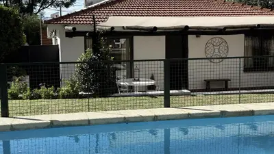 a fence next to a house with a swimming pool at CABAÑA PREMIUM in Villa Carlos Paz