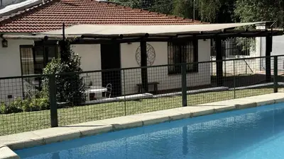 a fence next to a swimming pool with a house at CABAÑA PREMIUM in Villa Carlos Paz
