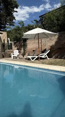 a white umbrella and two chairs and a pool at CABAÑA PREMIUM in Villa Carlos Paz