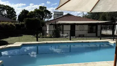a swimming pool with an umbrella and a house at CABAÑA PREMIUM in Villa Carlos Paz