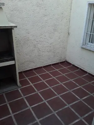 a room with a red tiled floor next to a building at El Dpto de Gabicito in Cordoba