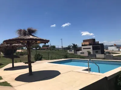 a swimming pool with a umbrella and a swimming pool at Carlos Paz, Villa Santa Cruz del Lago in Villa Carlos Paz