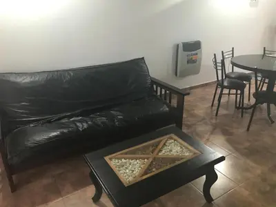 a black leather couch in a living room with a table at Carlos Paz, Villa Santa Cruz del Lago in Villa Carlos Paz