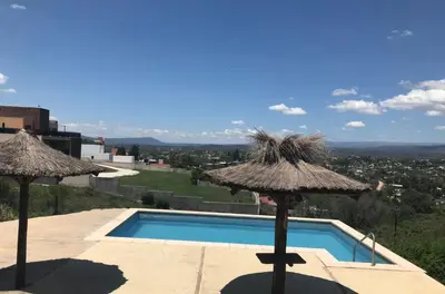 a swimming pool with two umbrellas and a swimming pool at Carlos Paz, Villa Santa Cruz del Lago in Villa Carlos Paz
