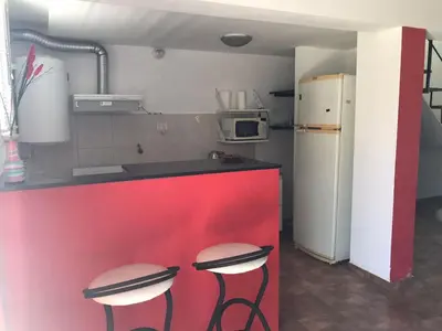 a kitchen with a red counter and two stools at Carlos Paz, Villa Santa Cruz del Lago in Villa Carlos Paz