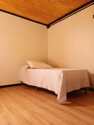 a bed in a room with a wooden ceiling at ALMA Posada in Almafuerte