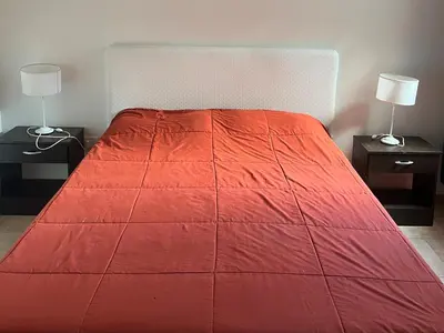 a red bed with two night stands and two lamps at Departamento Familiar!! Excelente entorno!! (#35) in Villa Carlos Paz