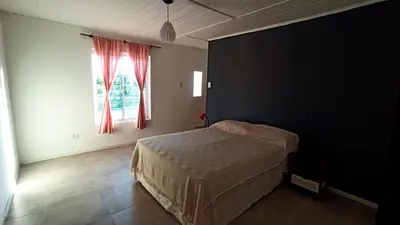 a bedroom with a bed and a window with red curtains at La casita de balcones in Villa Independencia