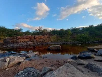 a river with rocks and trees in the background at La casita de balcones in Villa Independencia