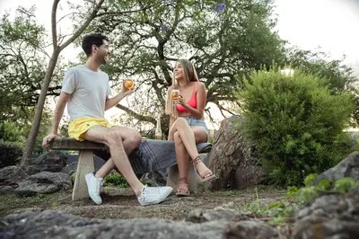 a man and a woman sitting on a bench with drinks at El Refugio Apart in Villa Serranita