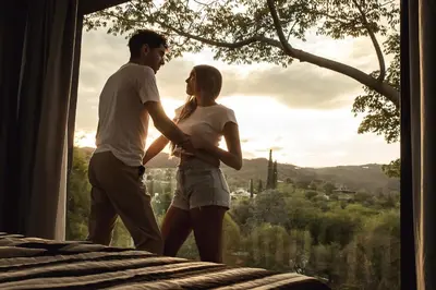 a man and a woman standing in front of a window at El Refugio Apart in Villa Serranita