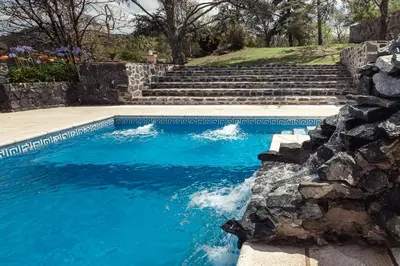 a swimming pool with stairs and blue water at El Refugio Apart in Villa Serranita