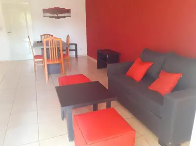 a living room with a black couch and red pillows at Departamentos Vila in Mina Clavero