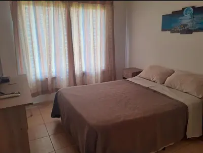 a bedroom with a bed and a window with curtains at Departamentos Vila in Mina Clavero