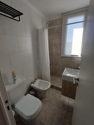 a white bathroom with a toilet and a sink at SERIETÁ 1 dormitorio con pileta y terraza in Cordoba