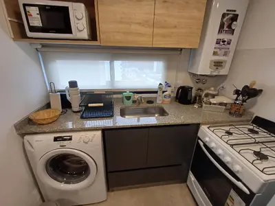 a kitchen with a sink and a washing machine at SERIETÁ 1 dormitorio con pileta y terraza in Cordoba