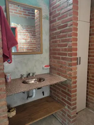 a bathroom with a sink and a brick wall at Departamento El Colibrí in Arroyo de Los Patos