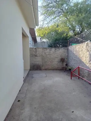 an empty courtyard with a fence and a red bench at La Tata in Alta Gracia