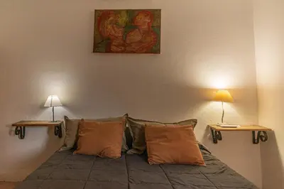 a room with a bed with two lamps and a painting at Meraki Classic in Villa Carlos Paz