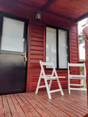 two white chairs sitting on the front porch of a red house at Refugios del Monte in Villa Yacanto
