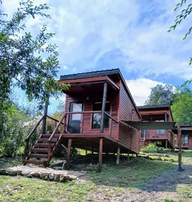 a log cabin with a staircase leading to the front of the house at Refugios del Monte in Villa Yacanto