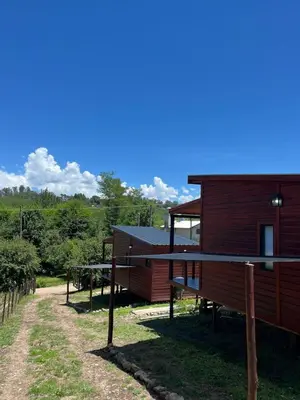 a wooden cabin with a dirt road next to it at Refugios del Monte in Villa Yacanto