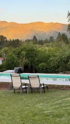 two chairs sitting in the grass next to a pool at La Jacinta posada suites in Santa Rosa de Calamuchita