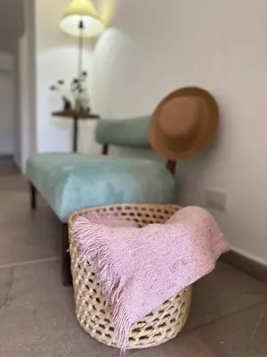 a living room with a chair and a basket with a blanket at La Jacinta posada suites in Santa Rosa de Calamuchita