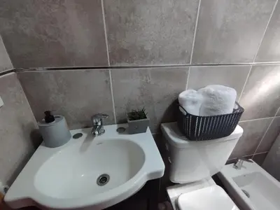 a bathroom with a white sink and a toilet at La Cabañita Córdoba in Villa Rumipal