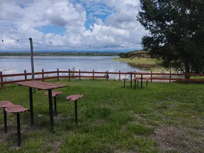 a picnic table and chairs in front of a lake at La Cabañita Córdoba in Villa Rumipal