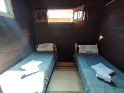 two beds in a small room with a window at La Cabañita Córdoba in Villa Rumipal