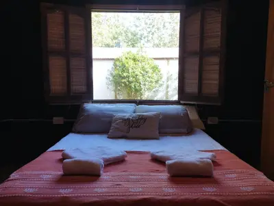 a bed with two pillows on it with a window at La Cabañita Córdoba in Villa Rumipal