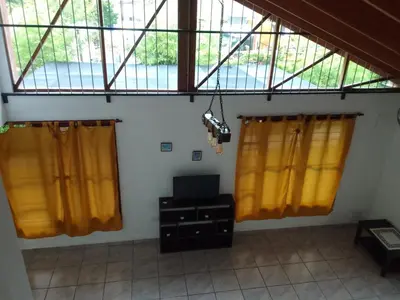 a room with two yellow curtains and a television at El Elyon Duplex in Santa Rosa de Calamuchita