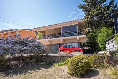 a house with a red car parked in front of it at Casa en Carlos Paz con pileta in Villa Carlos Paz