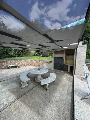 a patio with a table and two benches and an umbrella at Casa en Carlos Paz con pileta in Villa Carlos Paz
