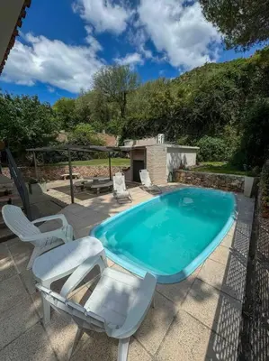 a swimming pool with two chairs and a table and avisor at Casa en Carlos Paz con pileta in Villa Carlos Paz