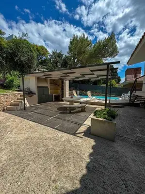 a pavilion with a picnic table and a pool at Casa en Carlos Paz con pileta in Villa Carlos Paz