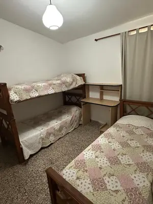 a room with two beds and a desk and a table at Casa en Villa Carlos Paz in Villa Carlos Paz