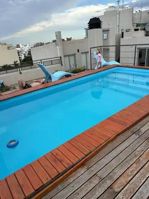 a little girl is standing next to a swimming pool at Departamento en Córdoba in Cordoba