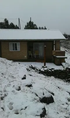 a house with snow on the ground in front of it at Cabañas & Suites 