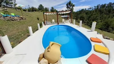 a blue swimming pool with chairs and a gazebo at Cabañas & Suites 