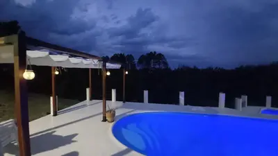 a blue swimming pool on a deck at night at Cabañas & Suites 