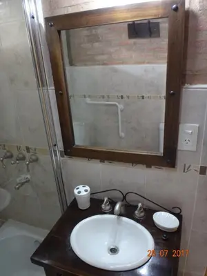a bathroom with a sink and a mirror at Cabañas & Suites 