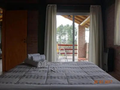 a bedroom with a large bed and a balcony at Cabañas & Suites 