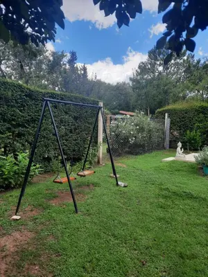 a swing set in the grass in a yard at El Marino in Merlo