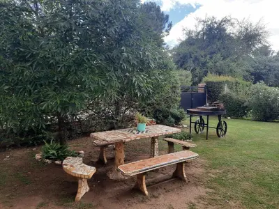 a picnic table and benches in a garden at El Marino in Merlo