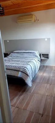 a bed in a room with a wooden floor at Cuatro Elementos Housing in Villa Parque Siquiman