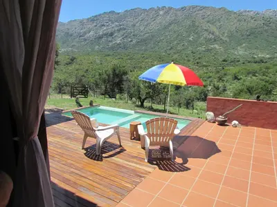 a patio with two chairs and an umbrella next to a pool at Cabañas San Miguel in Cortaderas